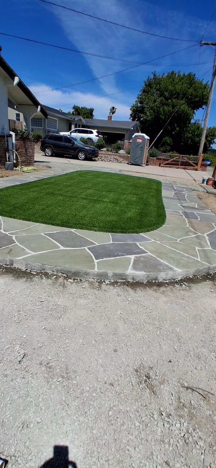 Finished turf area surrounded by clean natural-stone hardscape.